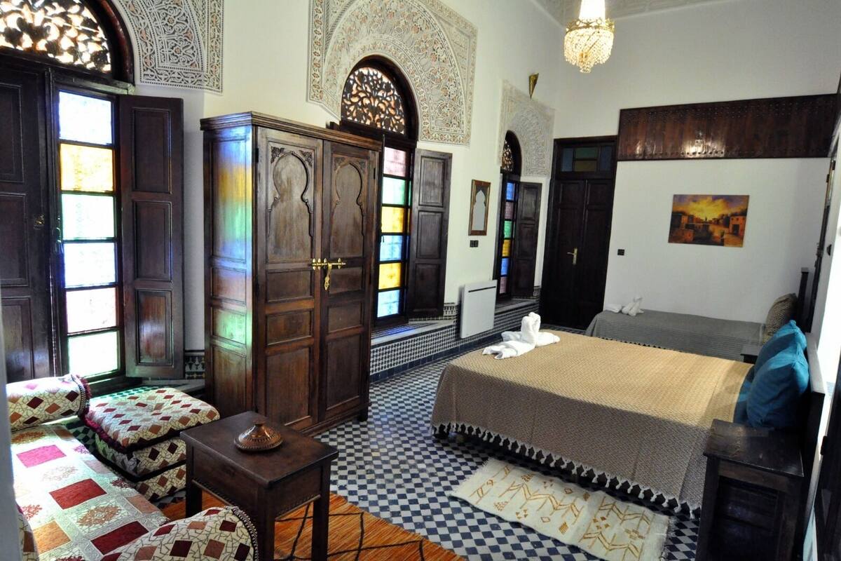 A traditional room with a checkered floor, a bed, a wardrobe, and a chandelier.