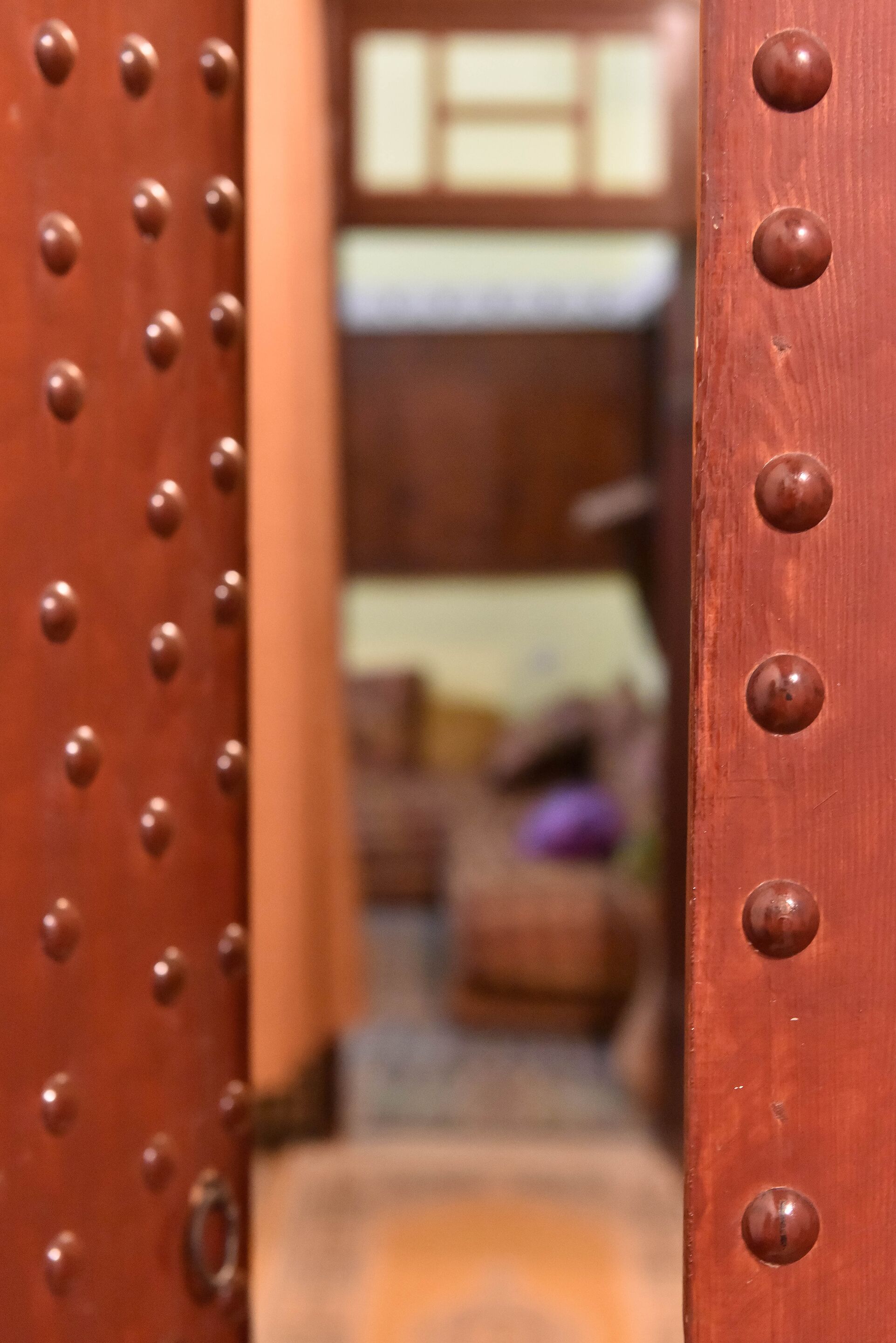 A close-up of a wooden door with riveted panels and a metal latch.