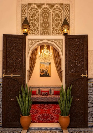 An ornate entryway with a red carpet, a chandelier, and two potted plants. - Riad Youssef (Fes)
