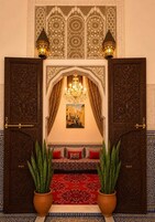Uma entrada requintada com tapete vermelho, um candelabro e duas plantas em vasos.
