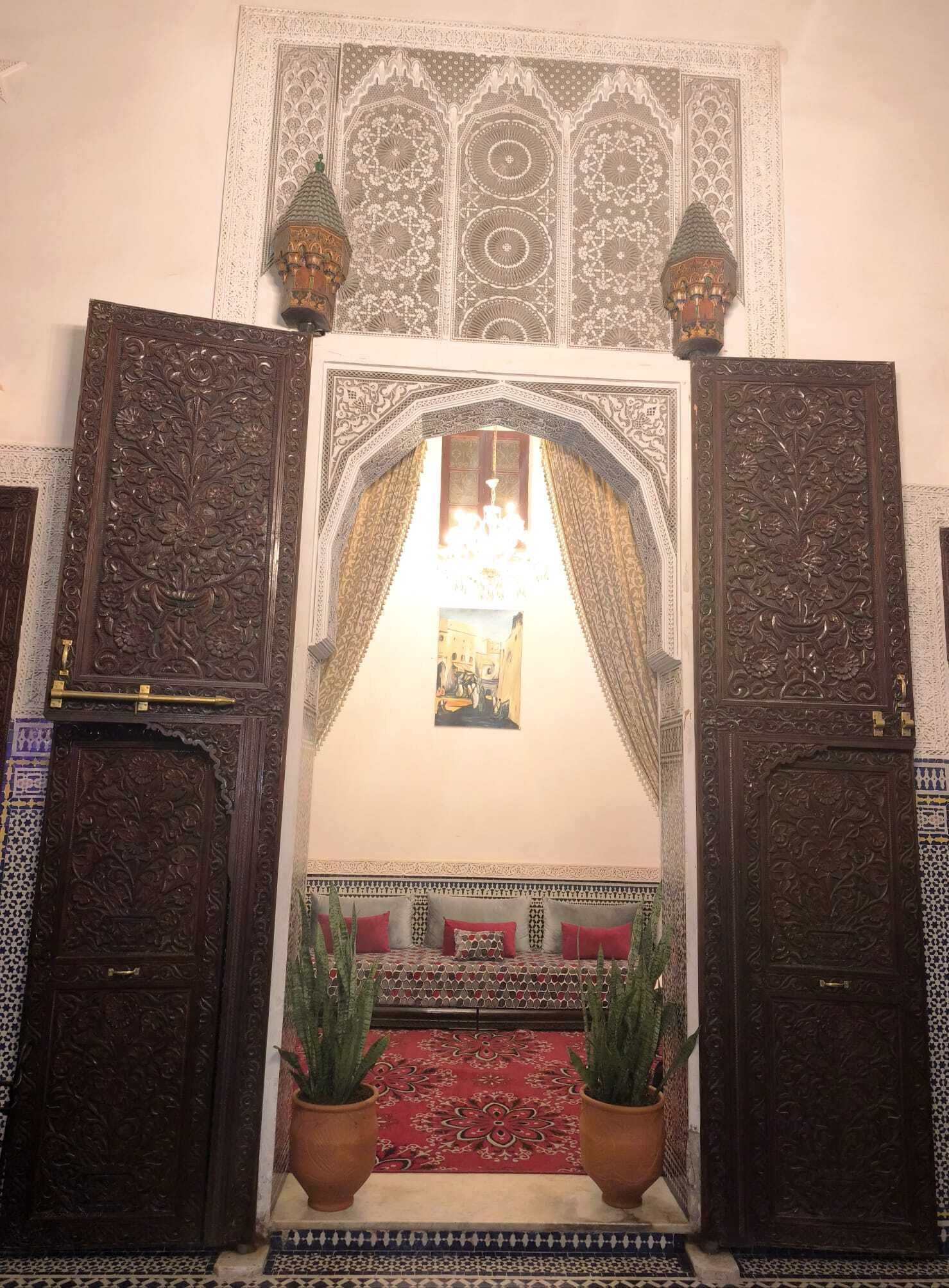 Um quarto ornamentado com um arco central, um lustre e duas plantas em vasos.
