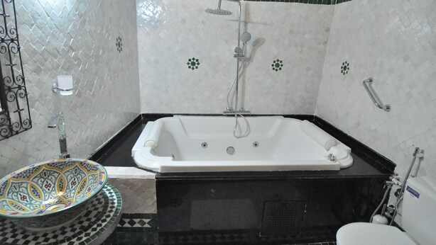 A bathroom with a bathtub, toilet, and a decorative sink.