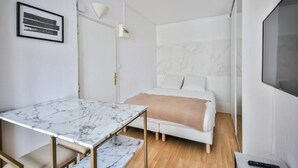 A compact bedroom with a bed, a small table, and a TV. - 33.Studio 2Pers#Sèvres-Lecourbe#Champ-de-Mars (Paris)