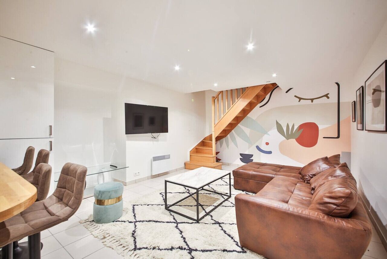 A modern living room with a sofa, coffee table, and a staircase leading to an upper level.