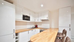 A modern kitchen with white cabinets, a wooden countertop, and a built-in oven. - 02.Duplex#2Bedrooms#Sèvres-Lecourbe#Champ-de-Mars (Paris)