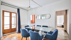 A modern room with a glass table surrounded by blue chairs, a large mirror, and a wooden floor. - 22.Appartement 6Pers#Sèvres-Lecourbe#Champ-de-Mars (Paris)