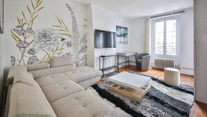 A modern living room with a sofa, a coffee table, a TV, and a painting on the wall. - 22.Appartement 6Pers#Sèvres-Lecourbe#Champ-de-Mars (Paris)