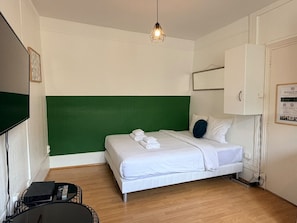 A hotel room with a bed, a green accent wall, a white ceiling light, and a white cabinet. - 41.Studio 2Pers#Sèvres-Lecourbe#Necker (Paris)