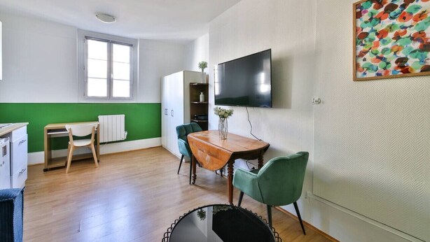 A modern, well-lit room with a wooden dining table, two chairs, a TV mounted on the wall, and a window providing natural light. - 41.Studio 2Pers#Sèvres-Lecourbe#Necker (Paris)
