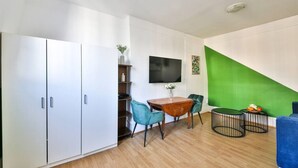 A compact living space with a dining area, a TV mounted on the wall, and a green accent wall. - 41.Studio 2Pers#Sèvres-Lecourbe#Necker (Paris)