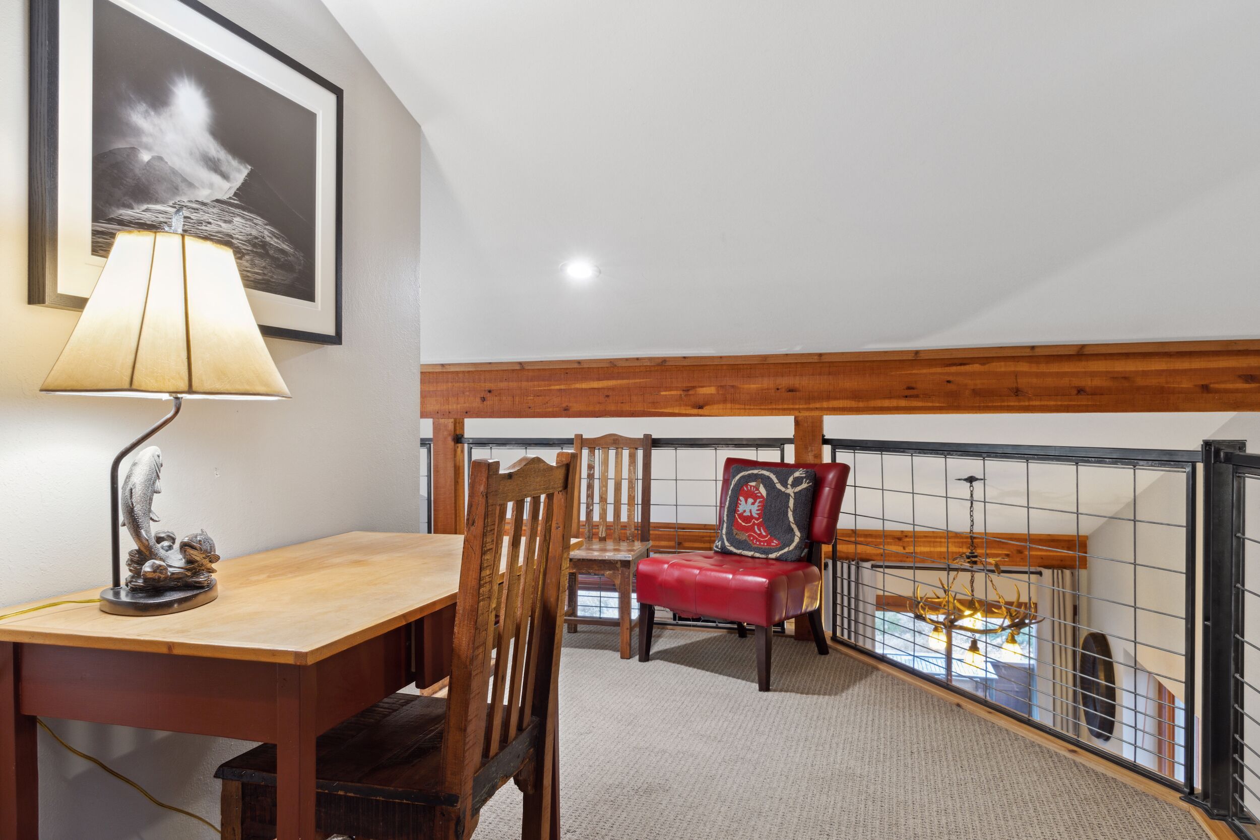 A dining area with a wooden table and chairs, a lamp, and a framed picture on the wall.