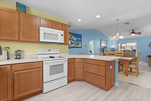 A kitchen with wooden cabinets, a microwave, an oven, and a dining area with a table and chairs.