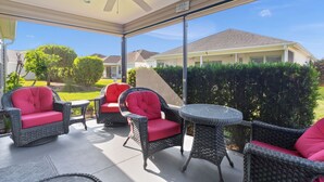 A covered patio area with wicker furniture and a ceiling fan. - Ranch Retreat: Luxury Living in Village Charm! (The Villages)