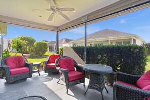 A covered patio area with wicker furniture and a ceiling fan. - Ranch Retreat: Luxury Living in Village Charm! (The Villages)