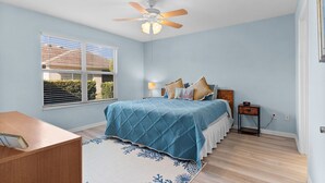 A bedroom with a bed, a nightstand, a desk, a ceiling fan, and a window with blinds. - Ranch Retreat: Luxury Living in Village Charm! (The Villages)