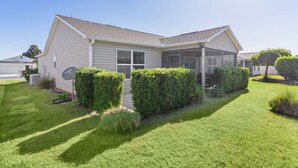 A single-story house with a covered porch, a satellite dish, and well-maintained landscaping. - Ranch Retreat: Luxury Living in Village Charm! (The Villages)