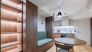 Een compacte keuken met een eethoek, een ingebouwd houten wandrek en een bank.