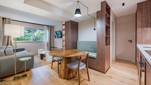 Een moderne, compacte woonruimte met een eethoek, bank en ingebouwde kasten.