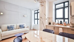 Een moderne woonkamer met een bank, een eettafel en een keukenhoek met een spoelbak en aanrecht.