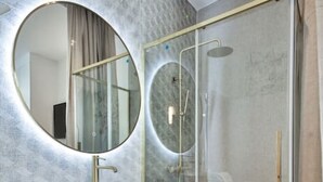 Een moderne badkamer met een gebogen wastafelmeubel, een ronde spiegel en een douche met glazen wanden.