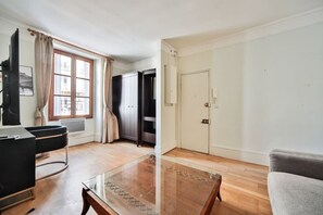 A spacious living room with a glass coffee table, a black sofa, a grey armchair, and a large window with curtains. - 12.Appartement 4Pers#Sèvres-Lecourbe#Necker (Paris)