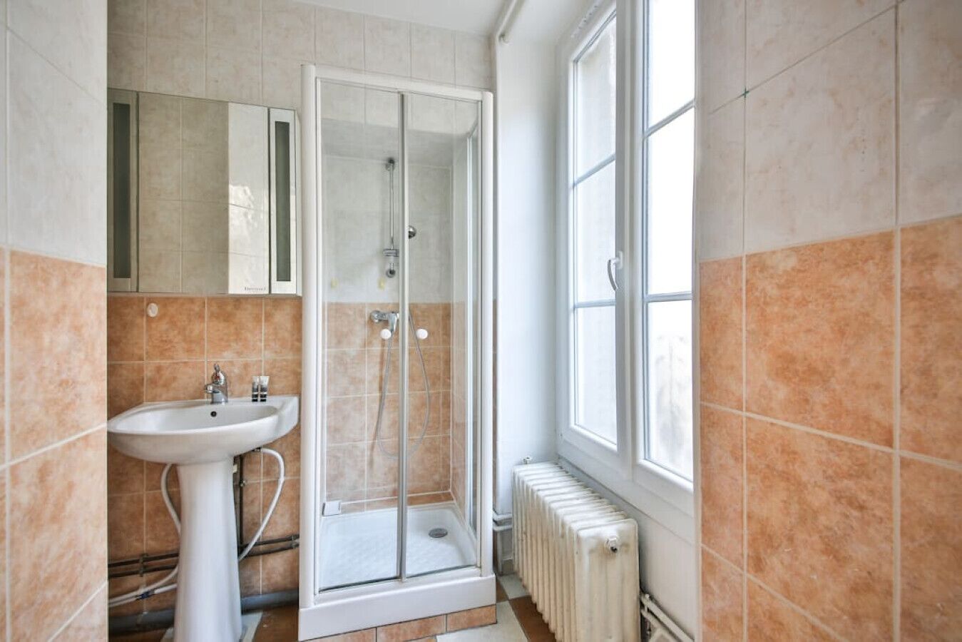 Ein Badezimmer mit Duschkabine, freistehendem Waschbecken und einem Fenster für natürliches Licht.