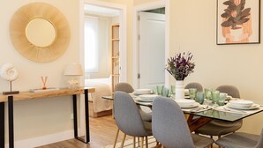 A dining area with a glass table, grey chairs, and a vase with flowers. - Genteel Home Jovellanos Terrace (Gijon)