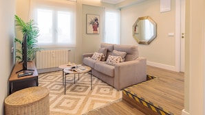 A living room with a sofa, a coffee table, a plant, and a radiator. - Genteel Home Jovellanos Terrace (Gijon)