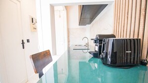 A compact kitchen with a glass table, a coffee maker, and a microwave. - Typical Parisian Studio in Le Marais (Paris)