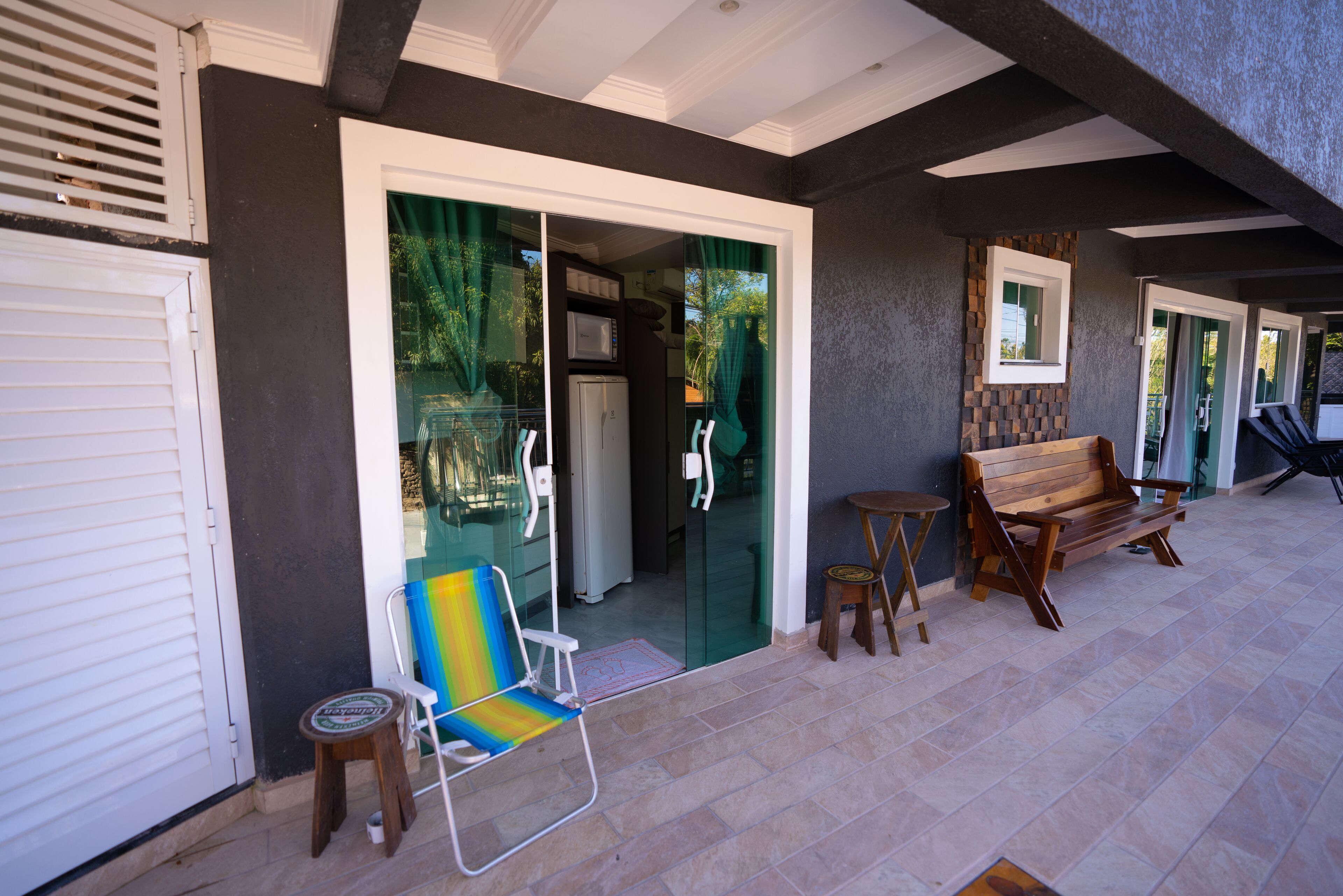 A covered outdoor seating area with a chair, a bench, and a small table.