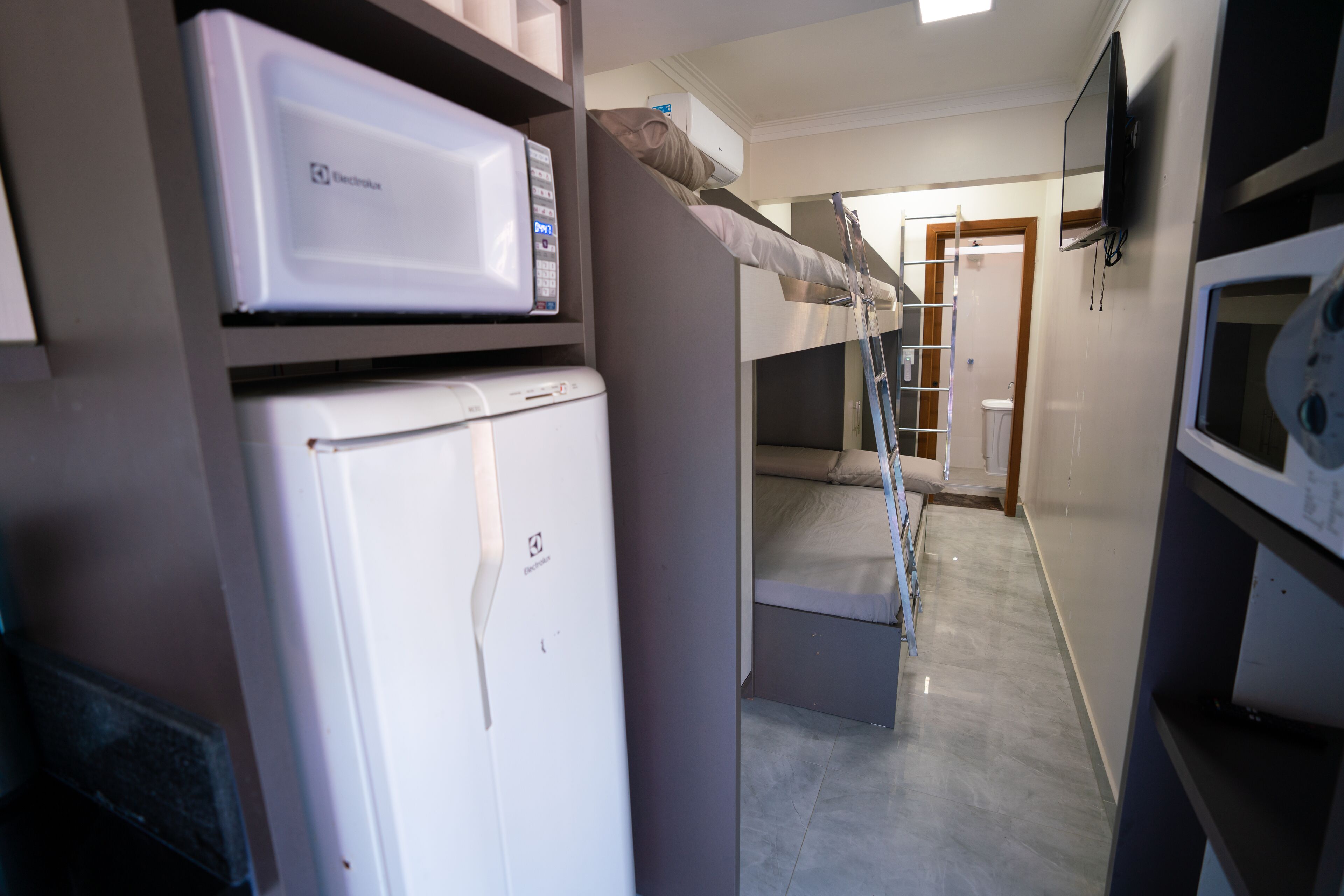 A narrow hallway with bunk beds, a microwave, and a refrigerator.