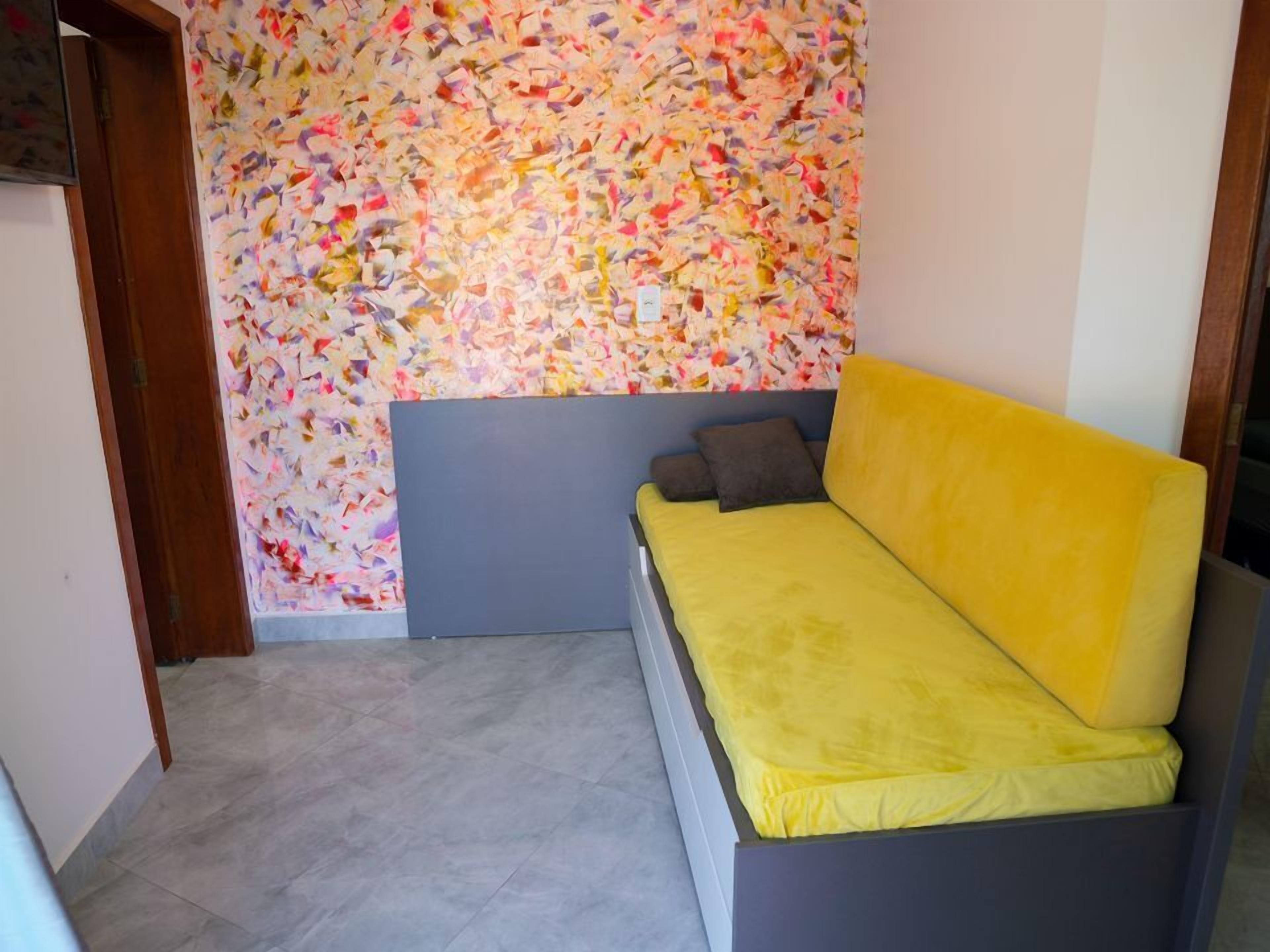 Ein Zimmer mit einem Bett, einer farbenfrohen abstrakten Wand und einem Fliesenboden.