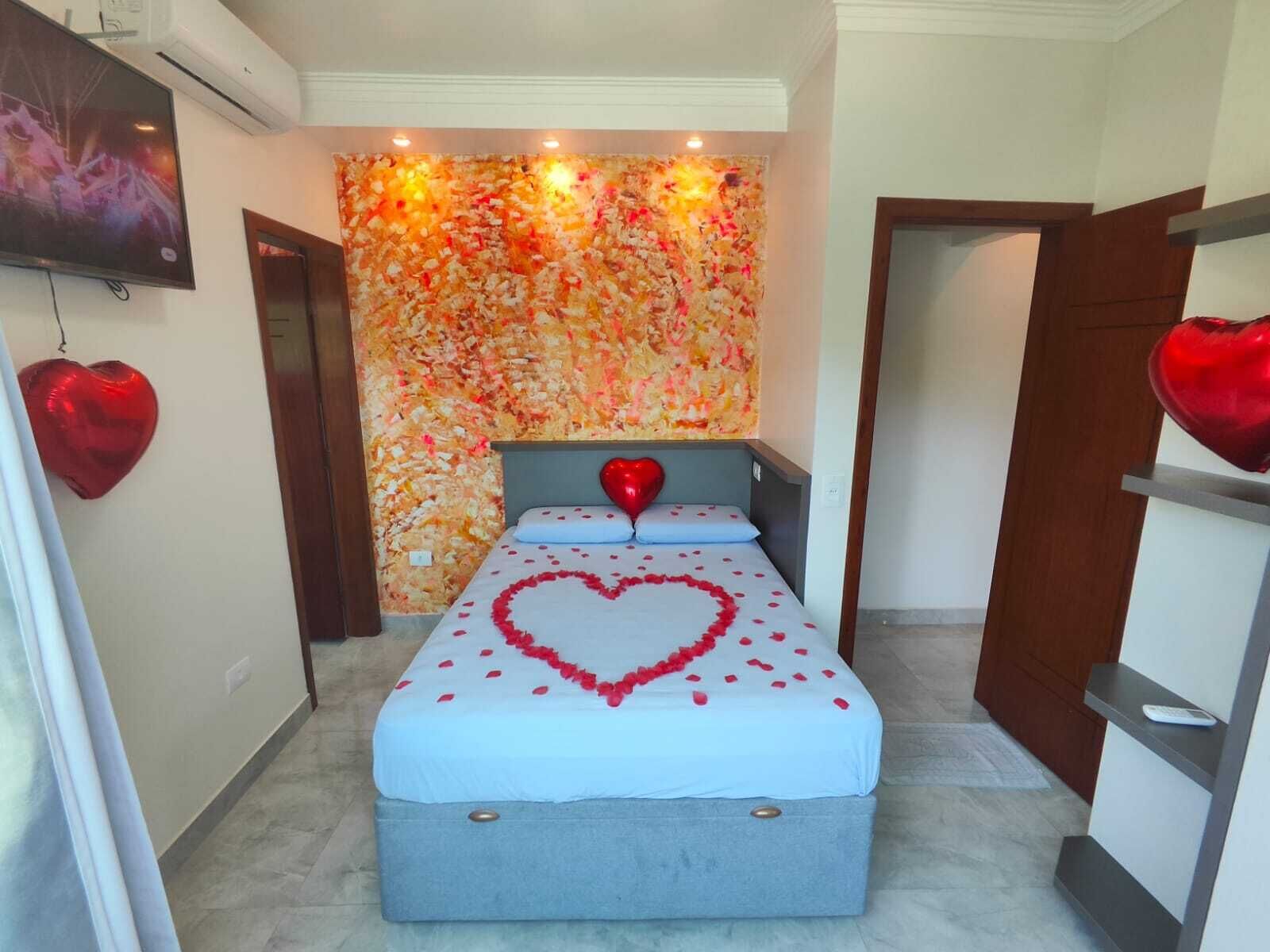 Un dormitorio con una cama, un adorno en la pared y un televisor.