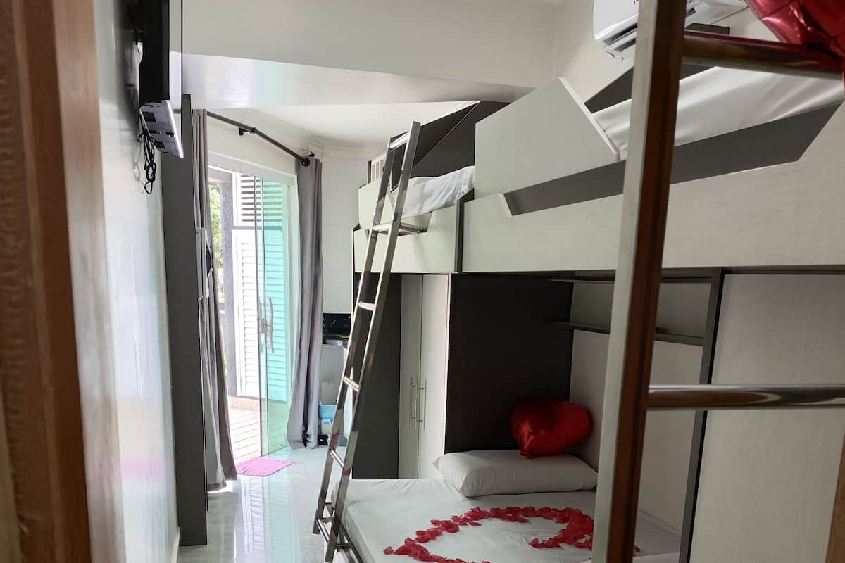 Habitación con literas, una escalera, un colchón blanco y una decoración con forma de corazón rojo sobre la cama.