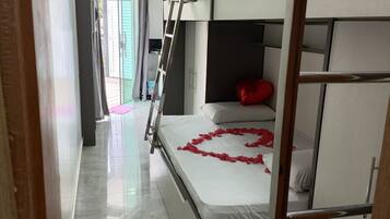 A bunk bed room with a ladder, a white mattress, and a red heart-shaped decoration on the bed.