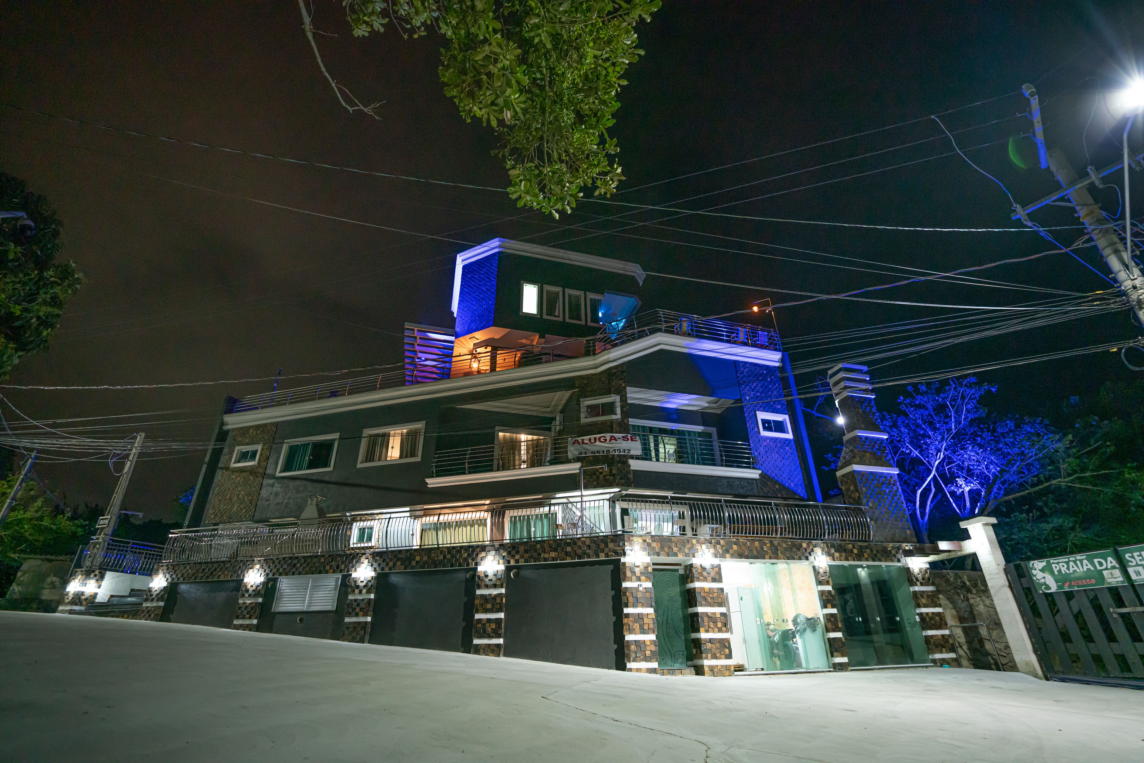A multi-story building with a balcony, a gated entrance, and a sign indicating a business or commercial use.