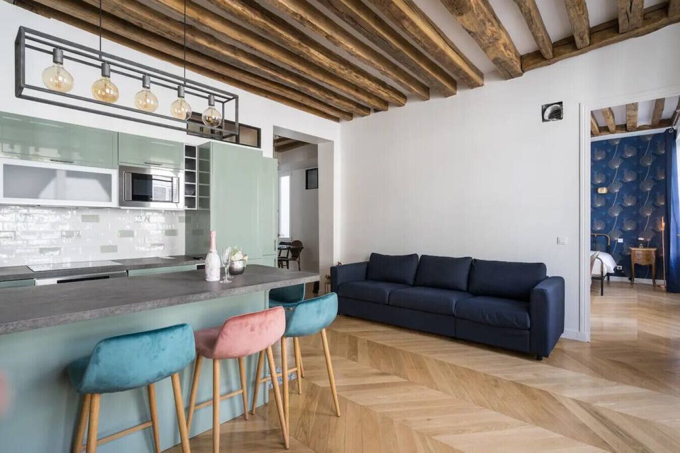 Eine moderne Küche mit Bar und einem dunkelblauen Sofa, außerdem Holzboden.
