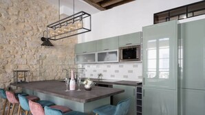 Een moderne keuken met een centraal eiland, barkrukken, een stenen muur en een groen kastje.