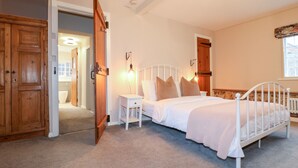 A bedroom with a white metal bed frame, a bedside table, a wooden wardrobe, and a door leading to another room. - 36 Main Street (Derby)
