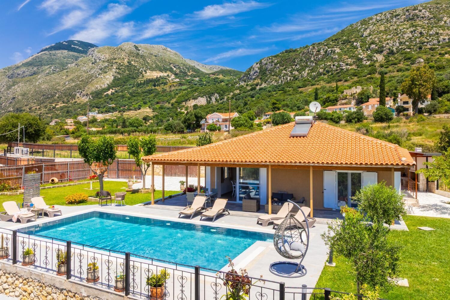 A villa with a swimming pool, outdoor seating, and a view of the surrounding hills.