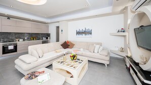 Ein modernes Wohnzimmer mit einem Ecksofa, einem Couchtisch mit Obst und einem Stadtbild an der Wand.