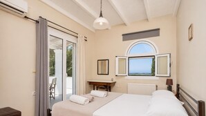 A bedroom with a bed, a desk, a chair, an air conditioning unit, and a window with a view. - Villa Mavrikia - Four Bedroom Villa, Sleeps 8 (Sfakera)
