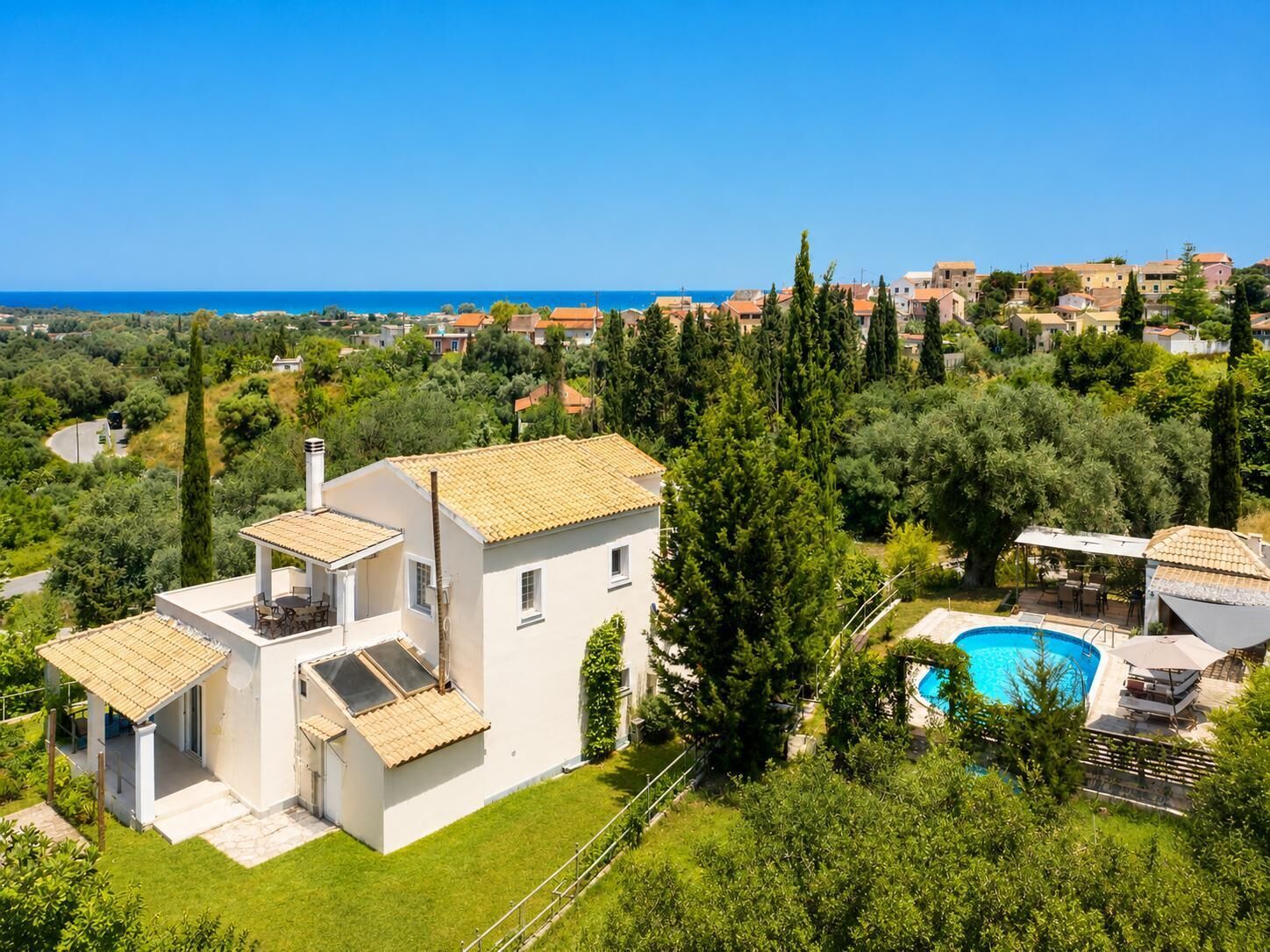 Eine moderne Villa mit Swimmingpool, umgeben von üppiger Vegetation und freiem Blick auf das Meer.