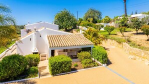 Eine weiße Villa mit einem Ziegeldach, umgeben von Grünflächen und einem Sandbereich.