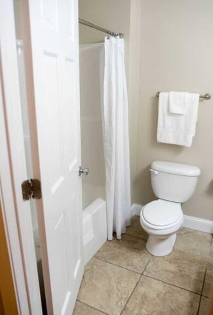A bathroom with a toilet, a shower curtain, and a towel rack.