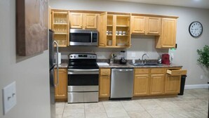 Una cocina moderna con armarios de madera, electrodomésticos de acero inoxidable y un reloj en la pared.