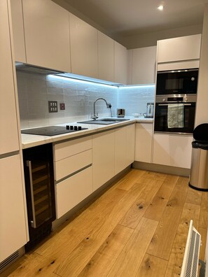 Eine moderne Küche mit weißen Schränken, einer Edelstahlspüle, einem Backofen von Bosch und einem eingebauten Geschirrspüler.