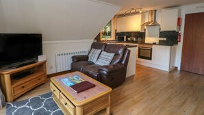 A living room with a leather sofa, a wooden coffee table, and a TV on a stand. - 27 Invergarry Lodges (Invergarry)