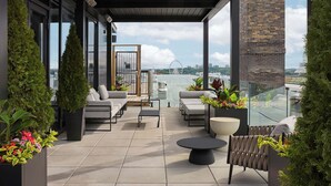 Terraza en la azotea con mobiliario exterior, plantas en macetas y vistas del horizonte urbano.