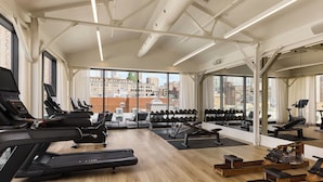 Un gimnasio con cintas de correr, máquinas de pesas y una máquina de remo.